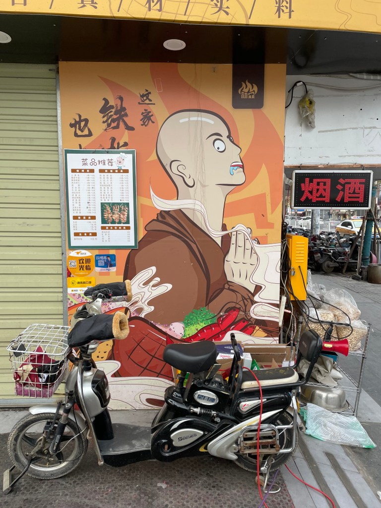 This photo shows a restaurant advertisement in Wuhan, China. Grunge aesthetic, scooters. 