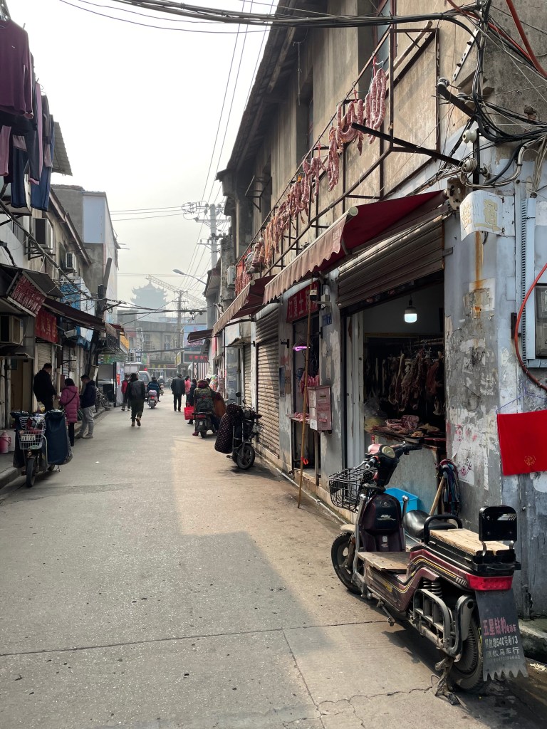 This photo shows a street in Wuhan, China in 2021. In the distances, one can see the Yellow Crane Tower. 