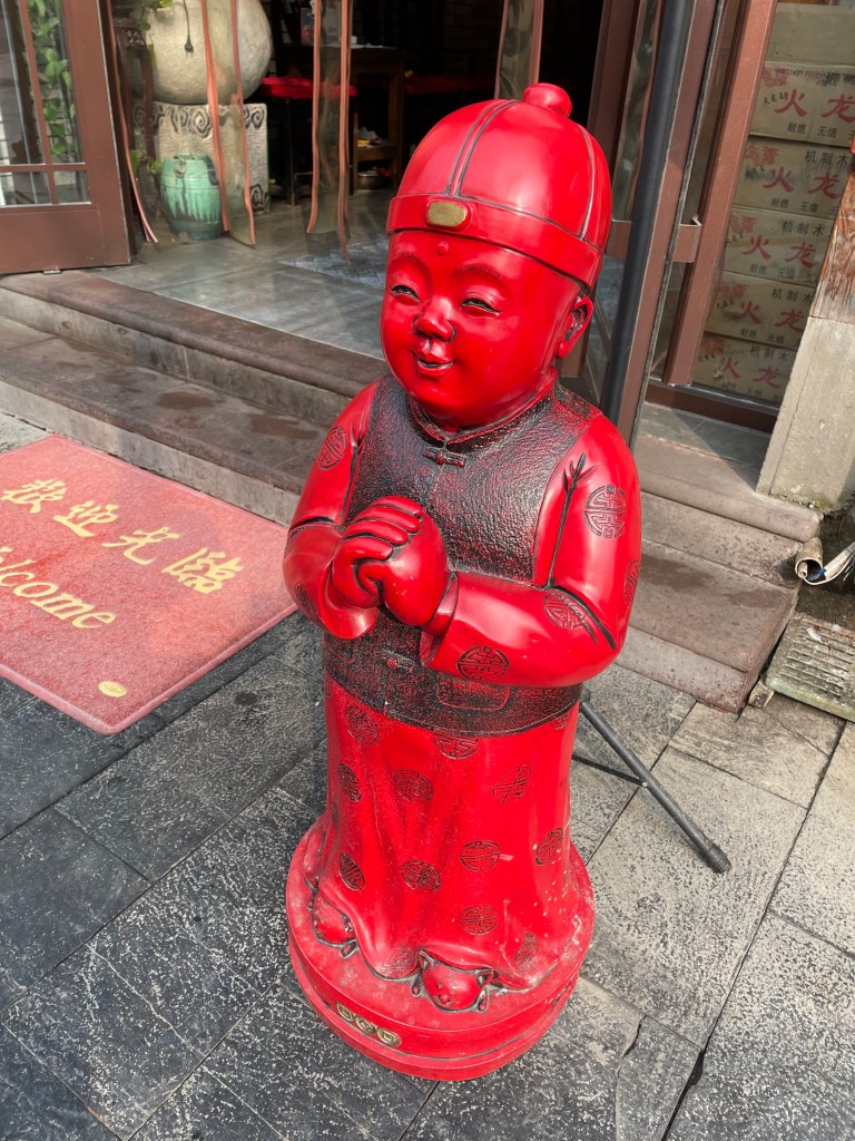 This is a photo of a little red statue on a Chinese commercial street. Taken in Wuhan in 2021.