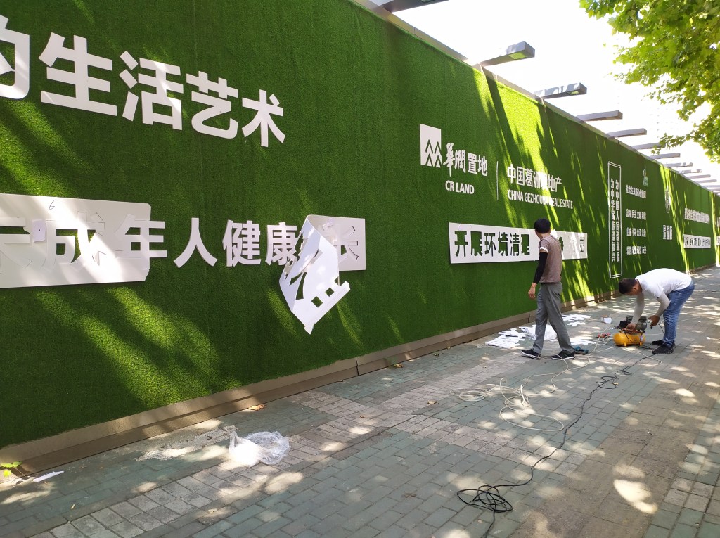 This picture shows men putting up propaganda slogans on a green construction wall in Wuhan, China in 2020.