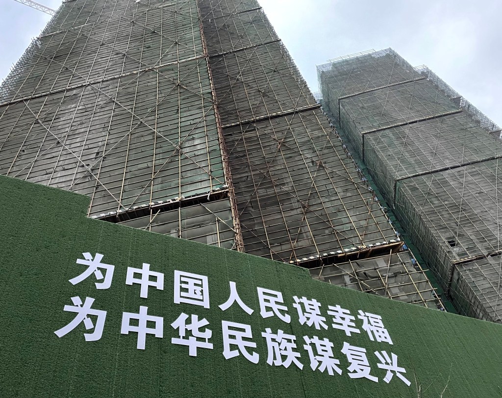 A photo of a green wall of propaganda slogans in Wuhan, China. It reads: ""Chinese people seek happiness, and the Chinese race seeks rejuvenation". This photo was taken in 2021.