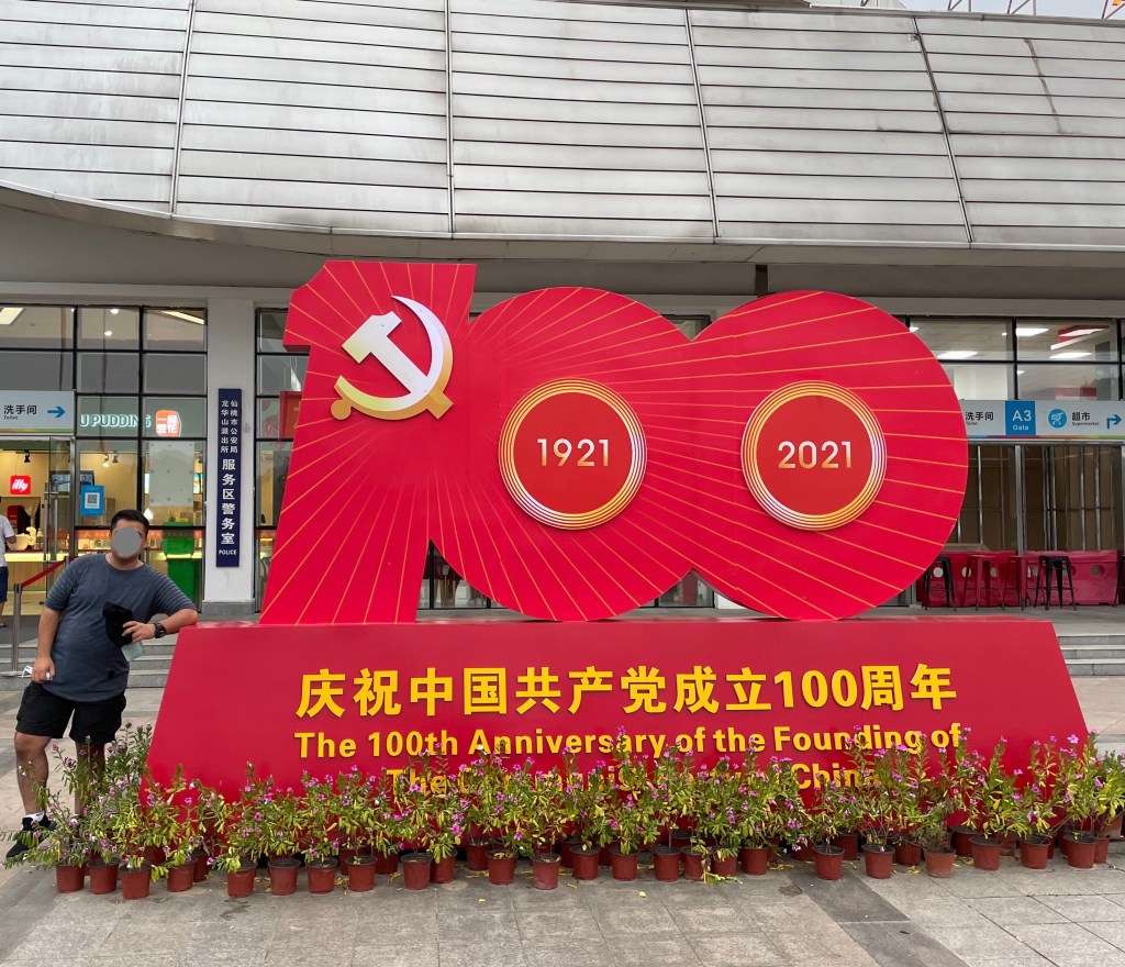 This photo shows a public monument commemorating the 100th anniversary of the founding of the Chinese Communist Party. 1921-2021. A man stands next to it in order to show the scale.