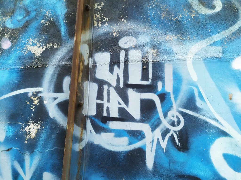 A photo of a Wenhua College campus wall. The graffiti reads "WU-HAN" the name of the city.